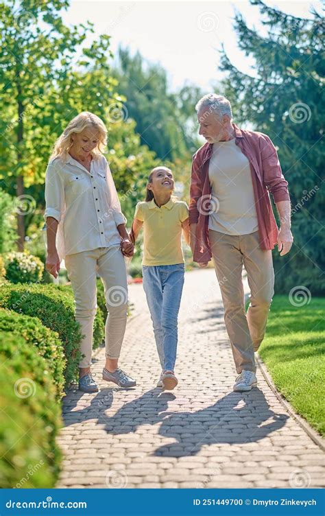 Familia Feliz Caminando De La Mano En El Parque Foto De Archivo