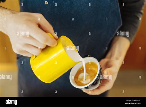 Close Up Of Barista Pouring Steamed Milk Into Coffee Cup Making Latte