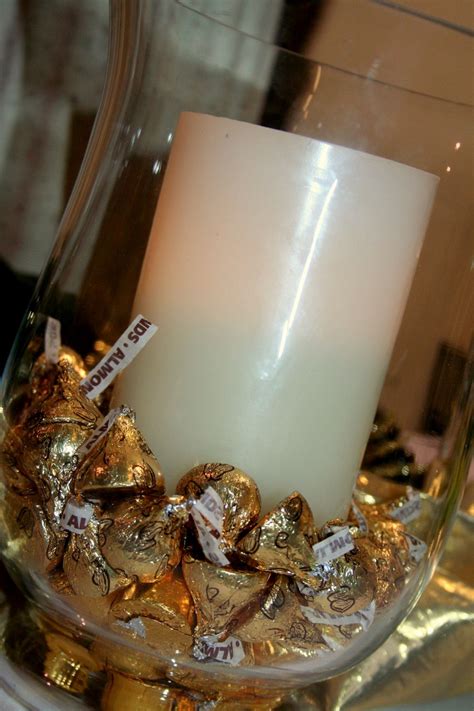 A Lit Candle Sitting On Top Of A Glass Container Filled With Gold And