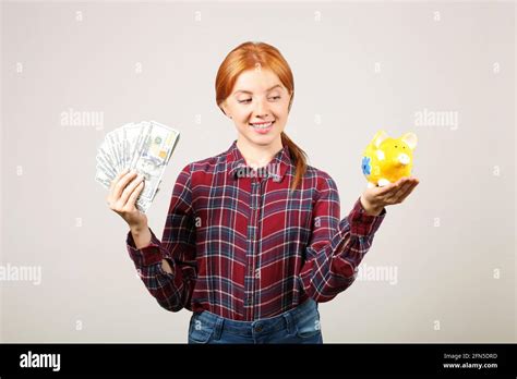 Portrait Of Young Beautiful Redhead Woman In Flannel Shirt Holding Stack Of Hundred Dollar Bills