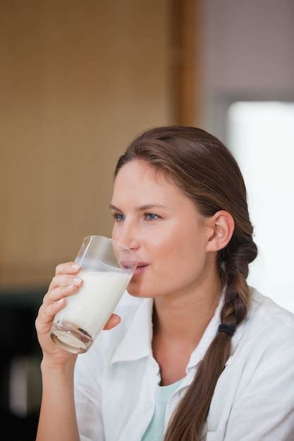 premium photo woman drinking a glass of milk while looking away