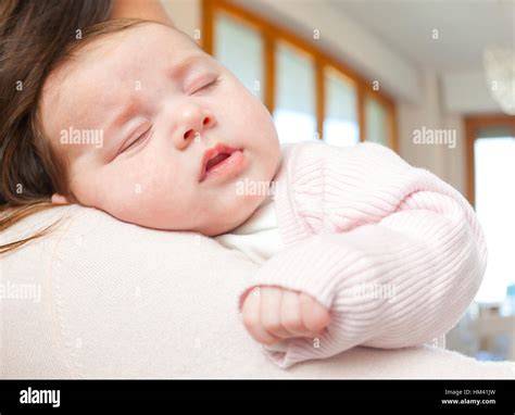 Portrait Of A Cute Newborn Baby Girl Sleeping On Her Mothers Shoulder