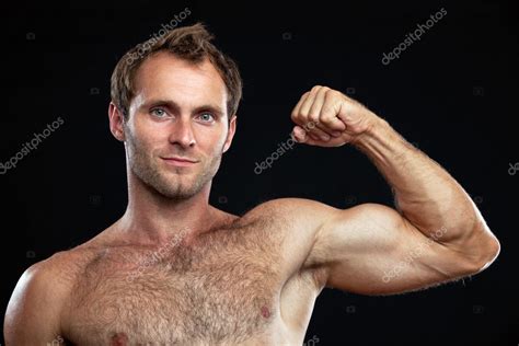 Closeup Portrait Of Muscular Man Flexing His Bicep Against Black Stock