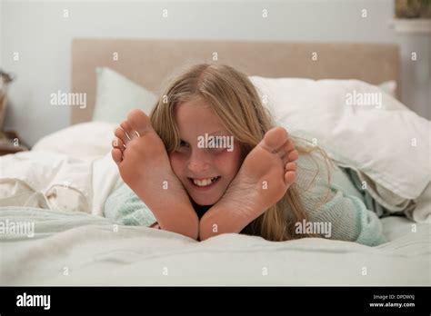 Porträt Eines Mädchens Auf Bett Zwischen Füßen Liegend Stockfotografie