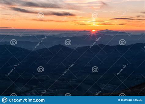 Distant Sunset Above Layers Of Mountains And Valleys With Mist And Fog