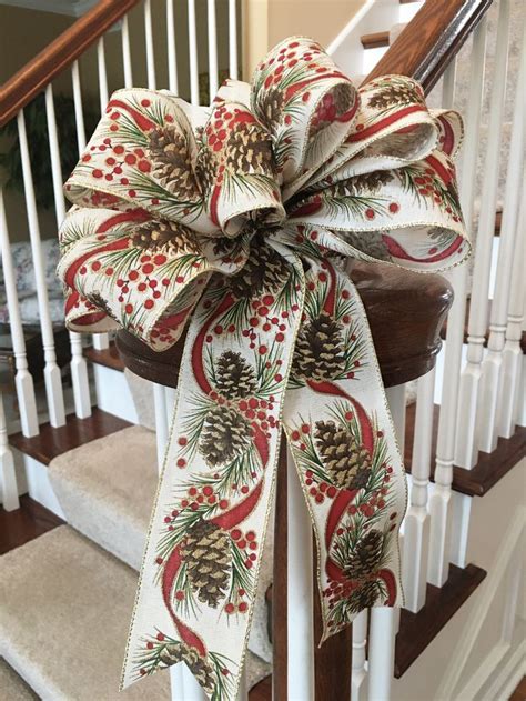 A Christmas Bow On The Banisters Of A House With Pine Cones And Berries