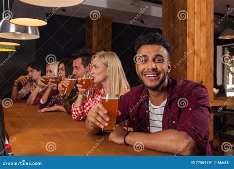 Young People Group In Bar Drink Beer Hispanic Man Hold Glass Toasting