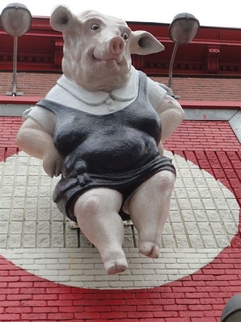 A Statue Of A Pig Sitting On Top Of A Red And White Tile Floor In Front