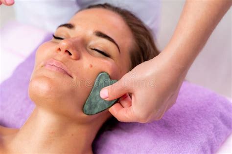 Relaxing Massage European Woman Getting Quartz Guache Face Massage In Spa Salon Side View