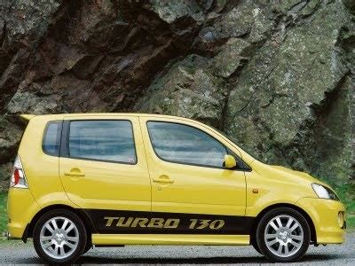 A Small Yellow Car Parked In Front Of A Large Rock Face With The Word