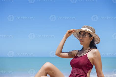 las mujeres jóvenes en bikini y sombrero de paja se sientan en la playa tropical disfrutando de
