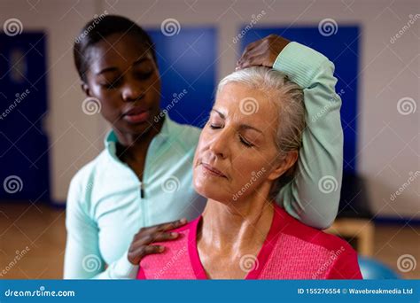 Female Physiotherapist Giving Neck Massage To Active Senior Woman In