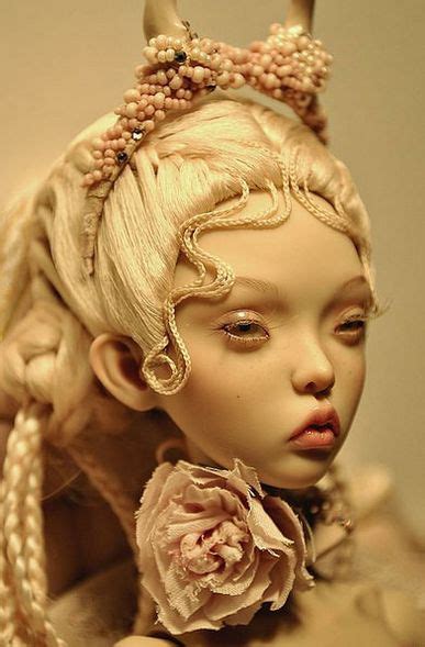 A Close Up Of A Doll With Long Blonde Hair And A Flower In Her Hair