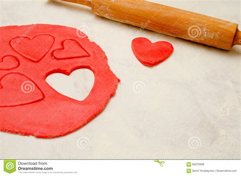 Red Dough With A Rolling Pin And Cut Out Hearts On A White
