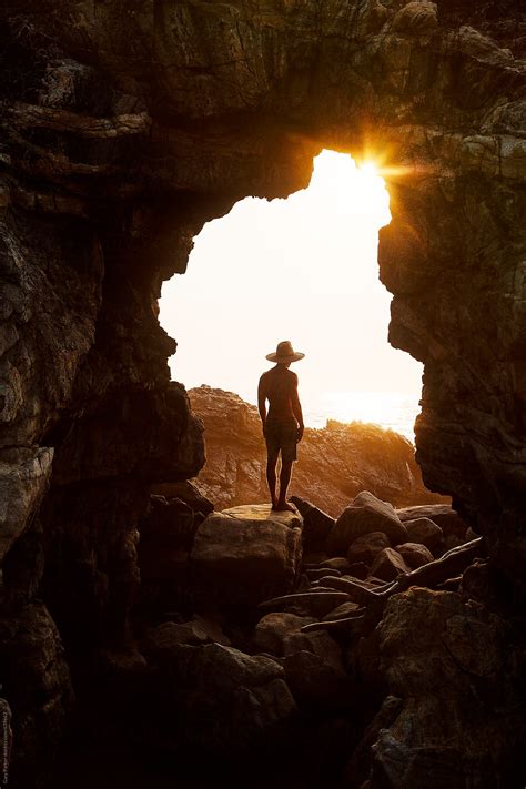 A Man Standing In A Cave Watching The Sun Set By Stocksy Contributor