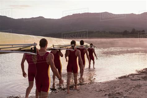 Rowing Team Carrying Scull Into Lake At Dawn Stock Photo Dissolve
