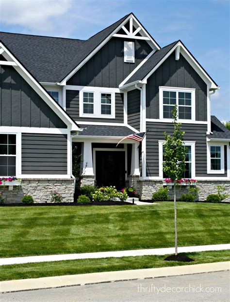 A Large Gray House With White Trim On The Front And Side Windows Grass