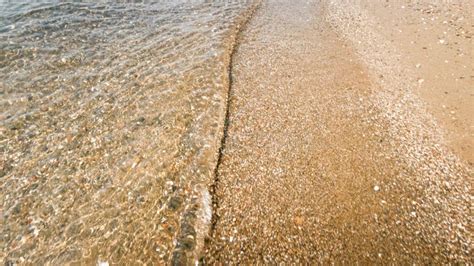 Closeup Image Of Calm Sea Waves Rolling Over Sandy Beach Stock Photo