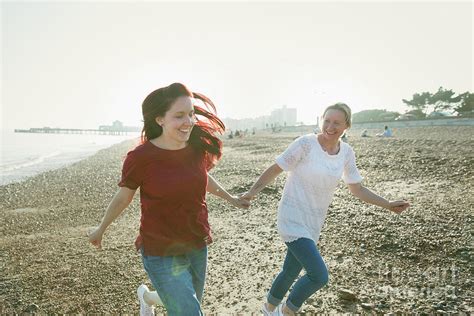 Playful Lesbian Couple Running On Beach Photograph By Caia Imagescience Photo Library
