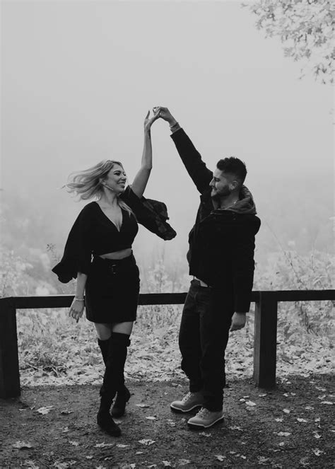 Black And White Photo Of Two People Holding Each Others Hands In The Air