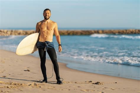 Premium Photo A Man Surfer With Naked Torso Standing On The Seashore
