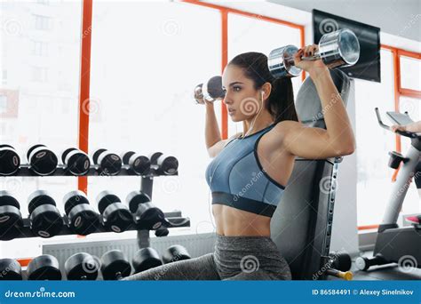 Beautiful Sporty Girl Lying On The Bench And Builds Muscle Arms Stock