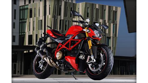 A Red And Black Motorcycle Parked In Front Of A Building With Tall