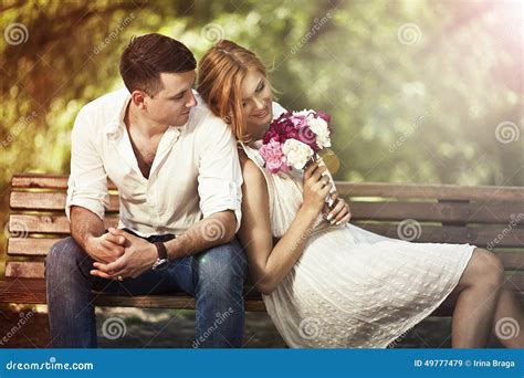 Young Beautiful Couple Sitting In The Park And Man Proposing Wo Stock