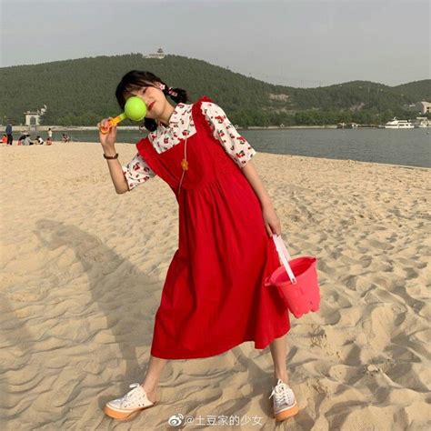 A Woman In A Red Dress On The Beach With A Tennis Ball And Water Bottle