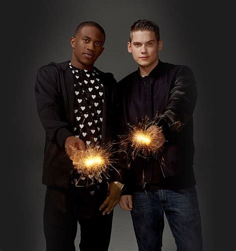 Two Men Standing Next To Each Other Holding Sparklers In Their Hands