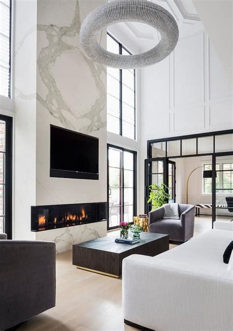 A Two Story White Marble Fireplace Fitted With A Tv Niche Is Lit By A