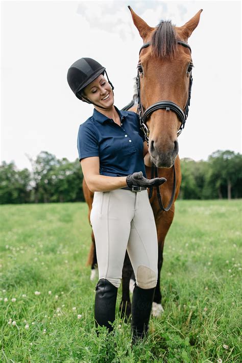 Young Woman Rider Standing Next To Her Horse And Smiling By Katie Joe