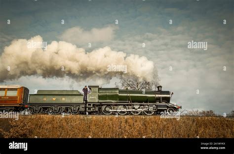 Side view, low-angle close up of vintage, UK steam train moving along the railway track in a ...