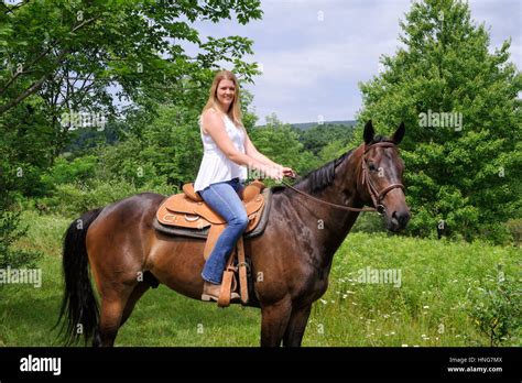 Girl On A Brown Western Saddle Horseback Riding Surrounded By Green