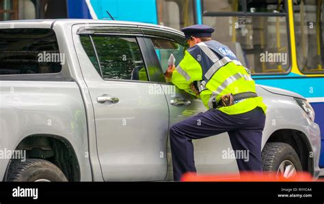 A Traffic Enforcer Talking To A Man Inside The Car In The Streets Of