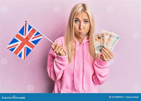 Jovencita Rubia Sosteniendo Bandera Del Reino Unido Puffing Mejillas Con Cara Divertida Foto