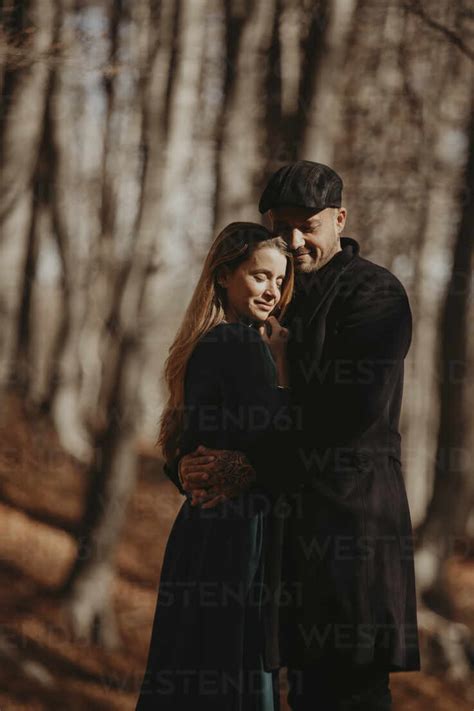 Boyfriend And Girlfriend Embracing In Forest During Sunny Day Stock Photo