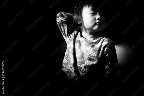 Cute Smiling Girl Looking Down Against Black Background Stock Photo