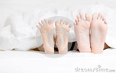 Close Up View Of Feet Of The Couple Lying In Bed Royalty Free Stock