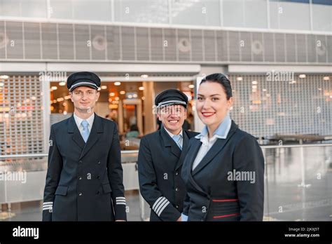 Happy Two Pilots And Stewardess Standing In The Airport Terminal Stock