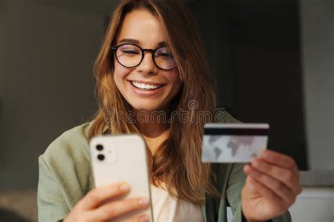 Happy Nice Woman Smiling While Using Mobile Phone And Credit Card Stock