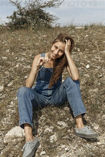 Caucasian Woman Wearing Overalls Sitting In Rocky Field Photo12 Tetra Images Ivan Ozerov