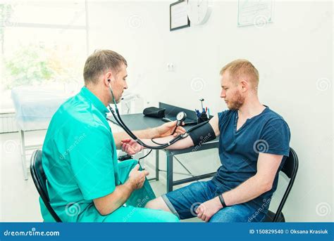 Male Doctor Using Sphygmomanometer With Stethoscope Checking Blood