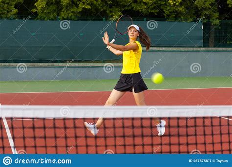 professional equipped female tennis player beating hard the tennis ball with racquet stock