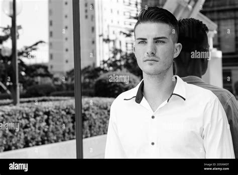 Young Handsome Man Thinking Against Glass Window Of Modern Building In
