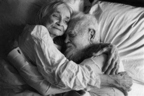 An Older Couple Cuddling In Bed Together