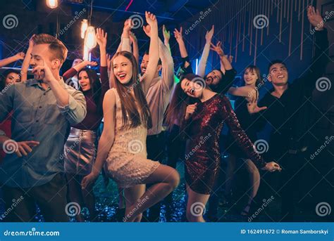 Portrait Of Cheerful Group Of People Mates Dancing In Nightclub Have