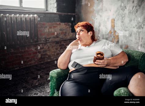 Fette Frau Sitzt In Einem Sessel Und Isst Süßigkeiten Übergewicht Ungesunde Lebensweise
