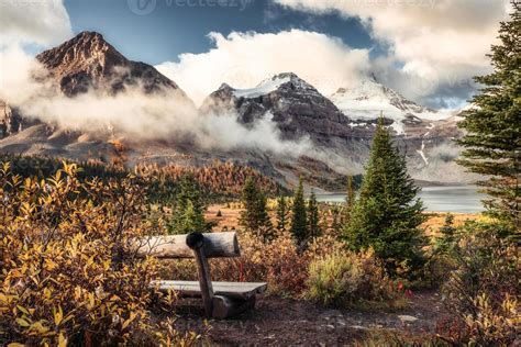 Mount Assiniboine On Lake Magog And Wooden Chair In Autumn Forest At