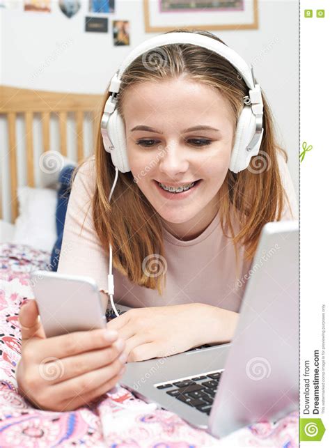 Teenage Girl Listening To Music Whilst Using Mobile Phone Stock Photo
